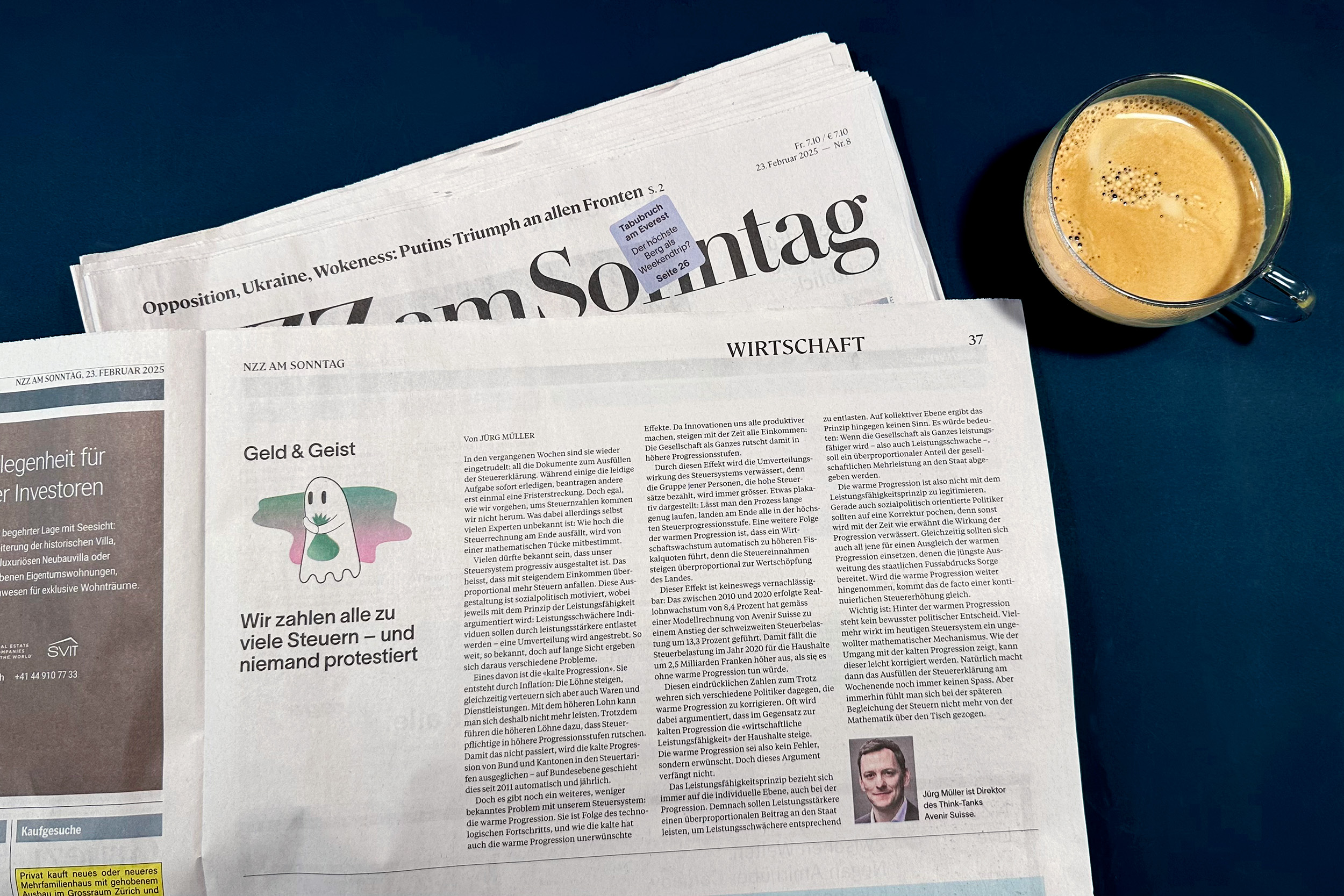 Aufgeschlagene Ausgabe von NZZ am Sonntag und Kaffeetasse.