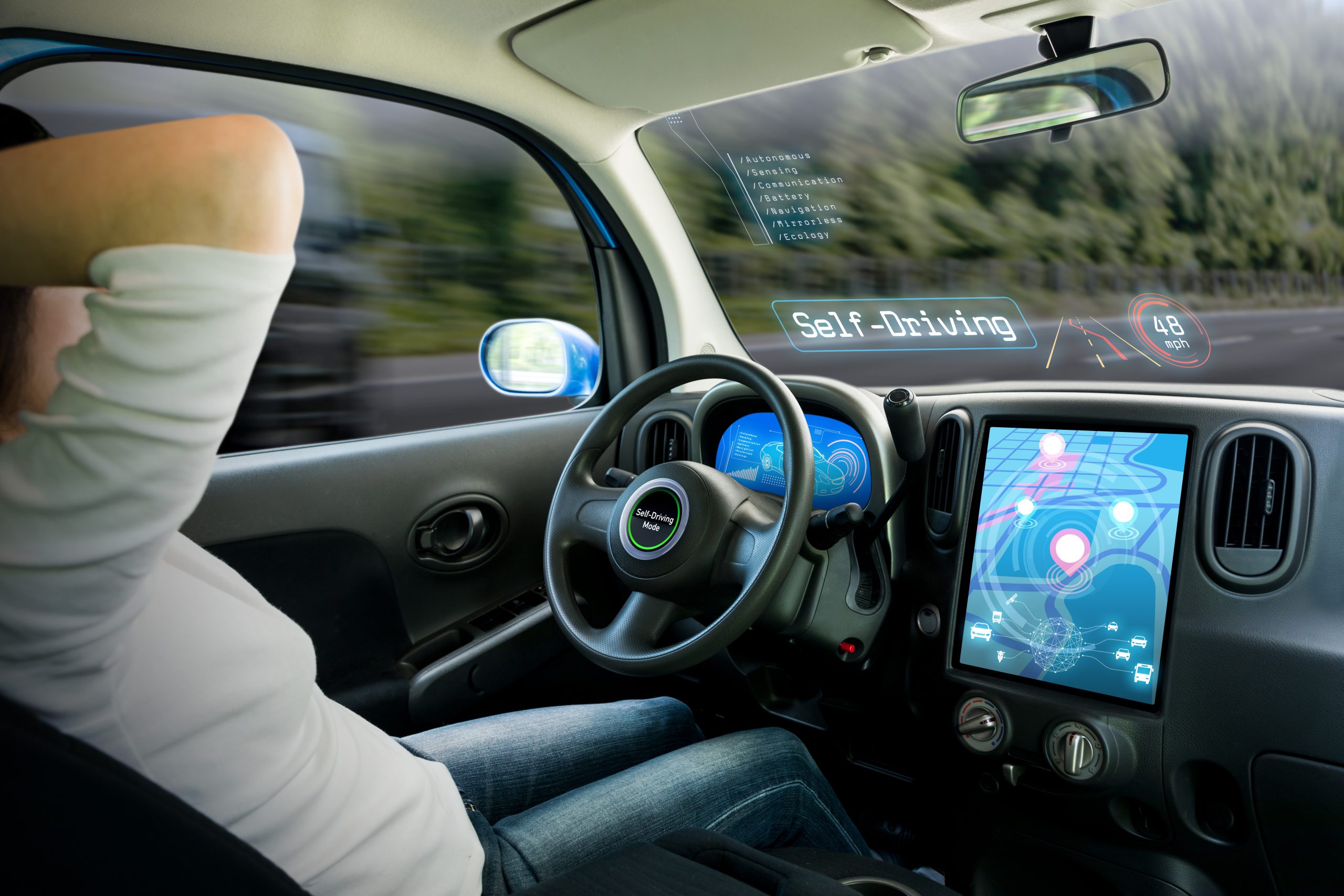 Cockpit eines autonomen Autos: Ein Fahrzeug im Selbstfahrmodus, während eine Fahrerin entspannt ist.